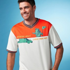 Young man wearing an orange, white and teal soccer jersey with Doug and Russell from Pixar’s Up. Text on the shirt reads “Adventure Awaits. Choose Your Path.”