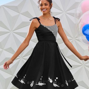 Young woman in a black and white Steamboat Willie-inspired dress standing in front of the Epcot ball with Mickey balloons.