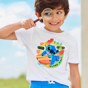 Young boy holding a magnifying glass wearing blue shorts and a white shirt  with a Stitch design and text reading “Aloha. Island Vibes”.