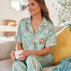 Brunette woman wearing Disney Princess Pajamas featuring Belle, Satin mint-green top and bottoms set with rose pattern and Princess Belle detail on the front left breast pocket.
