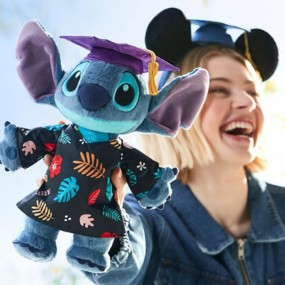Smiling woman in Mickey ears graduation cap holds a Stitch graduation plush. Celebrating graduation with Disney magic!