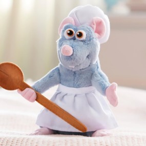 Ratatouille plush toy in apron, chef's hat, holding spoon on tan background.
