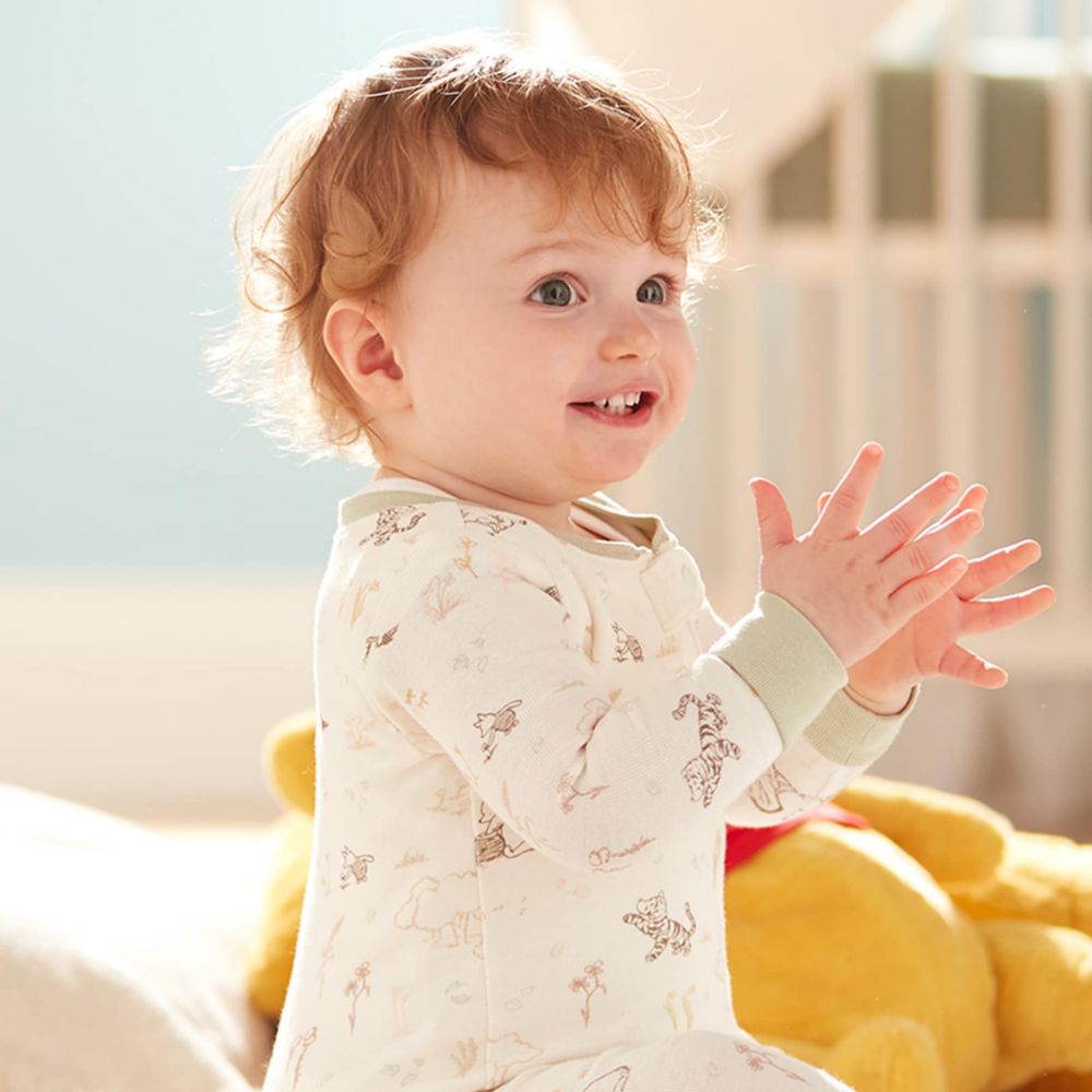 Dad wearing a black and white patterned Mickey shirt holding baby wearing a black, white and red patterned Minnie Mouse onesie.